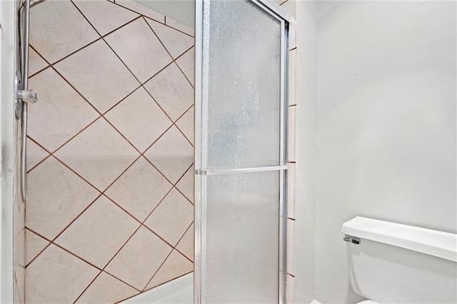 bathroom featuring toilet and a shower stall