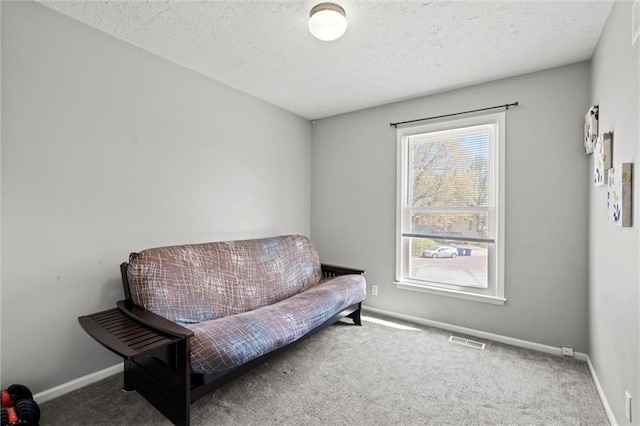 living area with baseboards, carpet, a textured ceiling, and visible vents