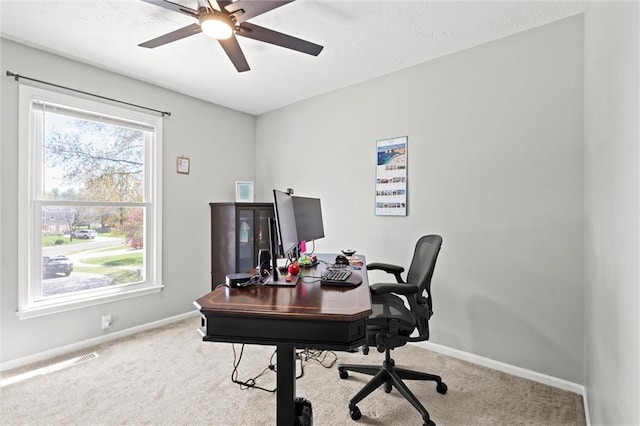 carpeted office space featuring baseboards and a ceiling fan