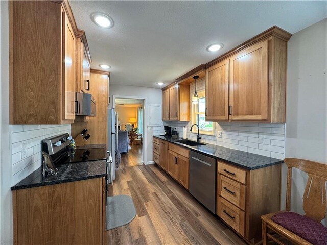 kitchen with a sink, dark wood-style flooring, recessed lighting, stainless steel appliances, and decorative backsplash
