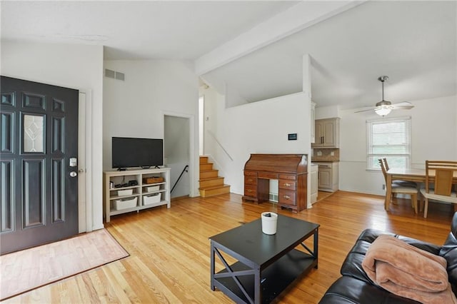 living room with visible vents, stairs, vaulted ceiling with beams, light wood-type flooring, and a ceiling fan