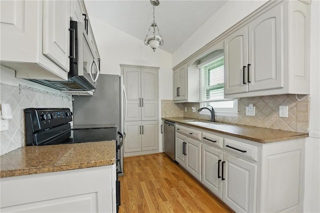 kitchen with decorative backsplash, appliances with stainless steel finishes, vaulted ceiling, light wood-type flooring, and a sink