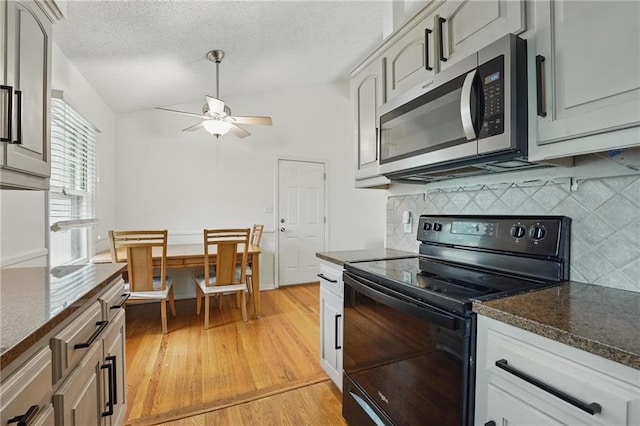 kitchen featuring decorative backsplash, ceiling fan, stainless steel microwave, light wood-style flooring, and black / electric stove