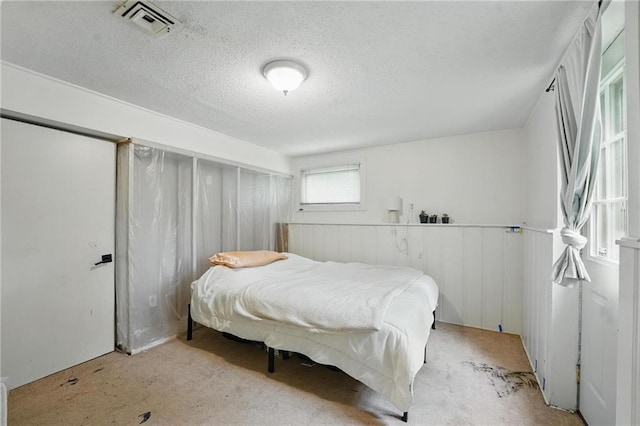 carpeted bedroom featuring a textured ceiling and visible vents