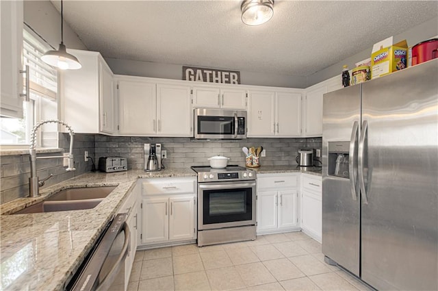 310 E 22nd St, Kearney, MO 64060 - kitchen with white cabinets, stainless steel appliances, a sink, and light tile patterned floors