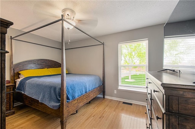 310 E 22nd St, Kearney, MO 64060 - bedroom with a textured ceiling, light wood-style floors, visible vents, and baseboards