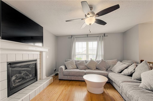 310 E 22nd St, Kearney, MO 64060 - living area featuring a tiled fireplace, ceiling fan, a textured ceiling, and light wood-style flooring