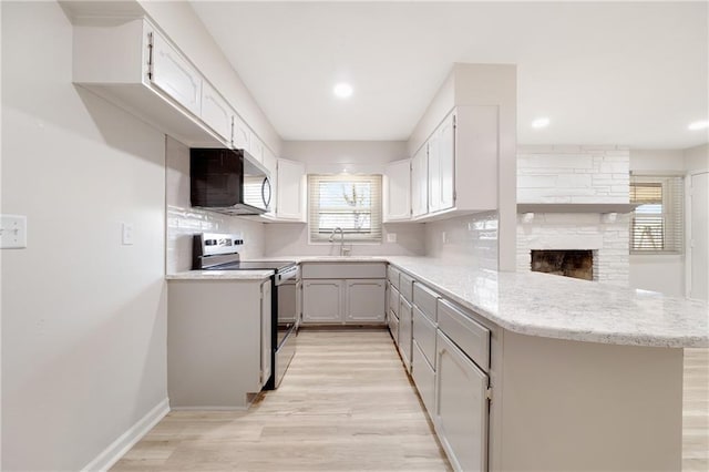 108 W Walnut St, Blue Springs, MO 64015 - kitchen featuring light wood-style flooring, tasteful backsplash, a peninsula, appliances with stainless steel finishes, and a sink