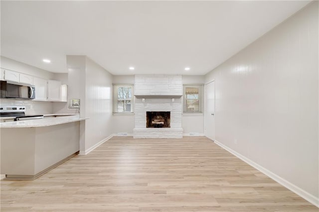 108 W Walnut St, Blue Springs, MO 64015 - unfurnished living room featuring recessed lighting, light wood-style flooring, baseboards, and a stone fireplace