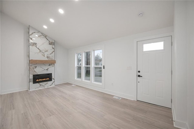unfurnished living room featuring visible vents, baseboards, a fireplace, vaulted ceiling, and wood finished floors