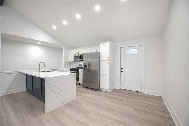 kitchen featuring light wood-type flooring, white cabinetry, appliances with stainless steel finishes, light stone counters, and a sink