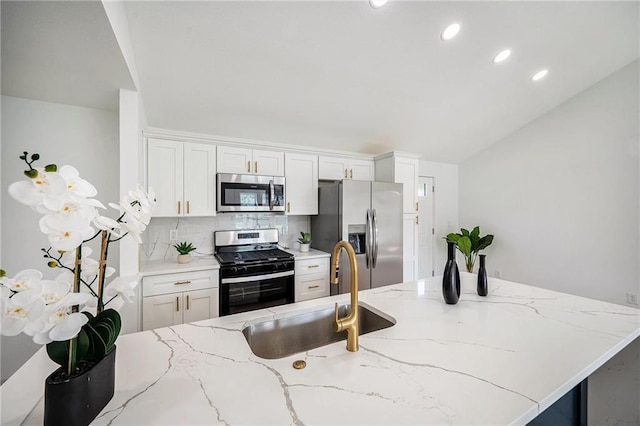 714 N Rogers St, Independence, MO 64050 - kitchen with appliances with stainless steel finishes, tasteful backsplash, white cabinetry, recessed lighting, and light stone countertops