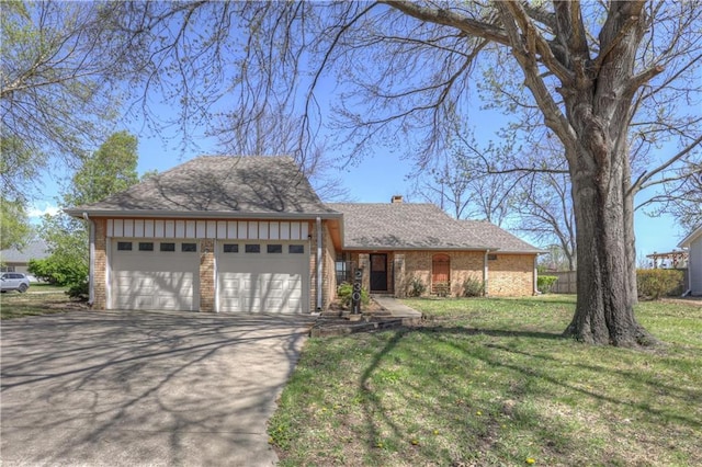 2301 S Stilwell St, Pittsburg, KS 66762 - view of front of property with a garage, a front lawn, brick siding, a chimney, and driveway