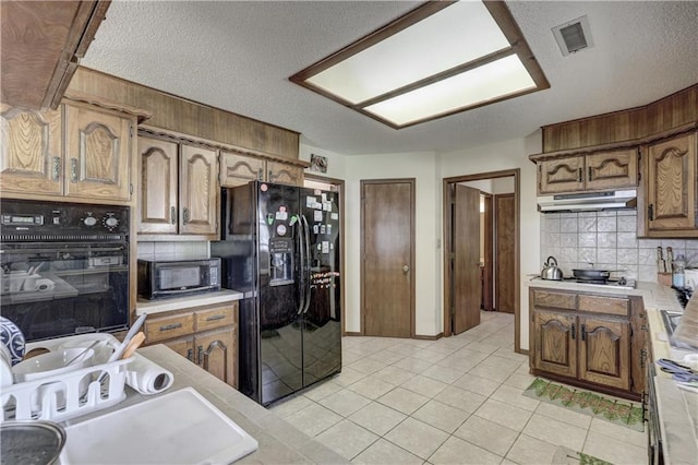 2301 S Stilwell St, Pittsburg, KS 66762 - kitchen with visible vents, black appliances, under cabinet range hood, light countertops, and decorative backsplash