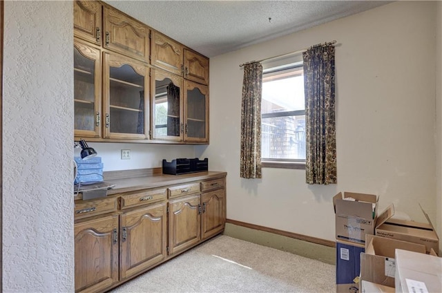 2301 S Stilwell St, Pittsburg, KS 66762 - interior space with glass insert cabinets, brown cabinetry, baseboards, and a textured ceiling