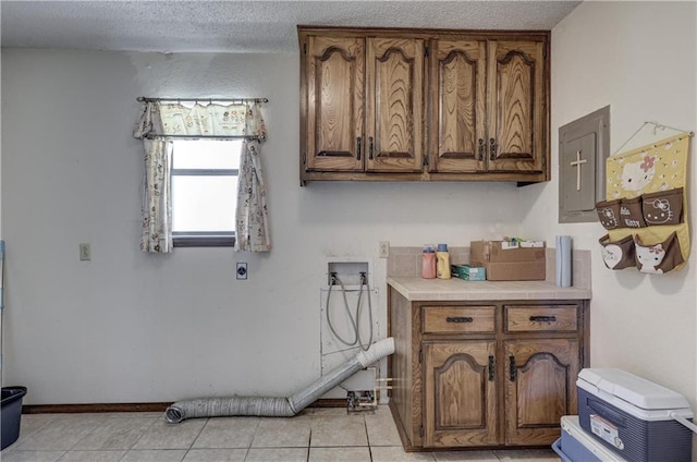 2301 S Stilwell St, Pittsburg, KS 66762 - laundry area with hookup for an electric dryer, light tile patterned floors, a textured ceiling, washer hookup, and cabinet space