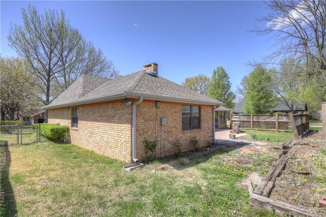 2301 S Stilwell St, Pittsburg, KS 66762 - view of side of home featuring a chimney, a lawn, brick siding, a fenced backyard, and a shingled roof