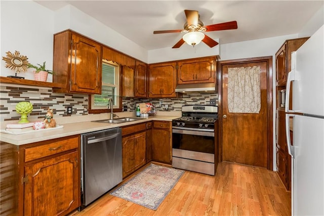 kitchen featuring under cabinet range hood, backsplash, a sink, appliances with stainless steel finishes, and ceiling fan