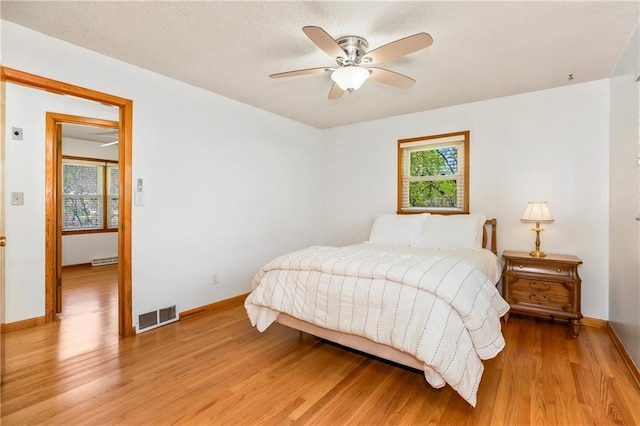bedroom featuring light wood-style floors, visible vents, baseboards, and multiple windows