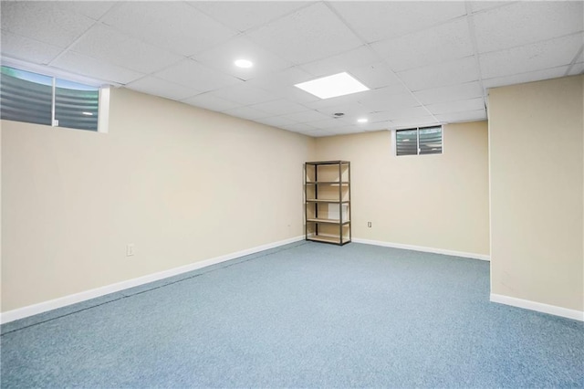 basement featuring baseboards, a paneled ceiling, and carpet flooring