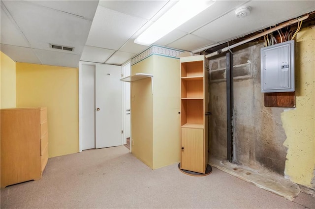 finished below grade area with carpet flooring, visible vents, electric panel, and a paneled ceiling