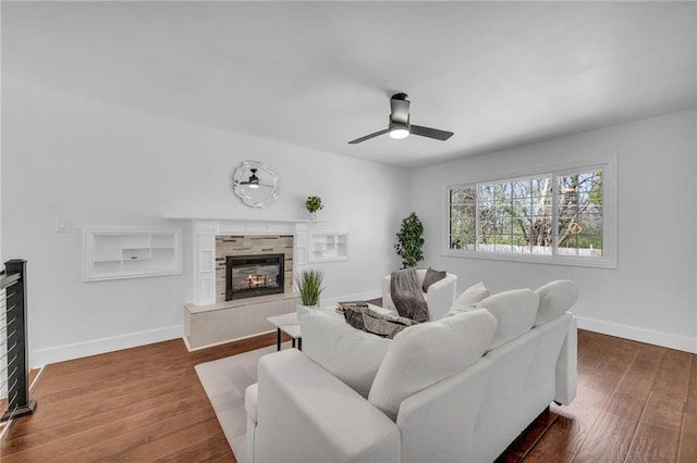 8608 E 91st St, Kansas City, MO 64138 - living room with ceiling fan, a fireplace, built in shelves, baseboards, and dark wood-style floors