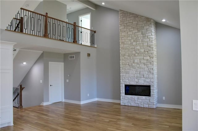 unfurnished living room with light wood finished floors, high vaulted ceiling, baseboards, and visible vents