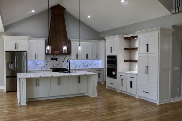 kitchen featuring white cabinets, multiple ovens, open shelves, and stainless steel fridge