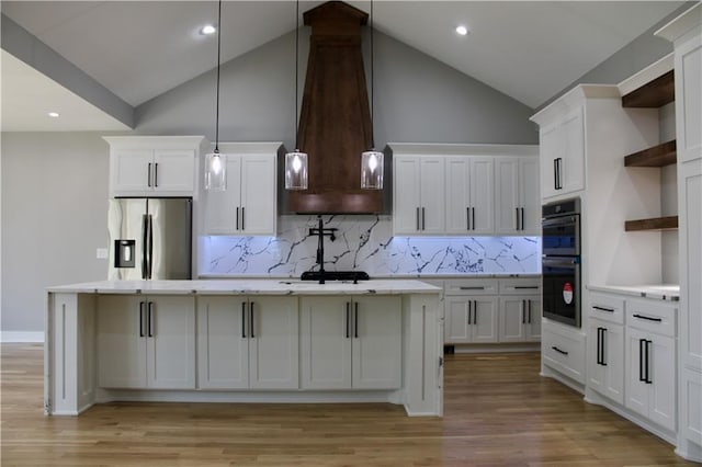 kitchen featuring open shelves, stainless steel fridge, a kitchen island with sink, double oven, and custom range hood