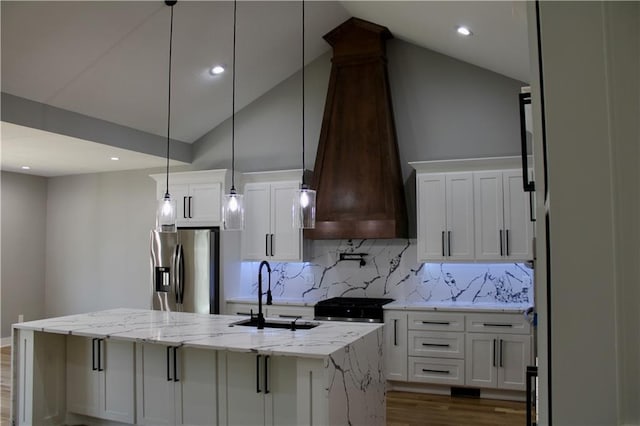 kitchen with white cabinets, a sink, stainless steel fridge, lofted ceiling, and custom range hood