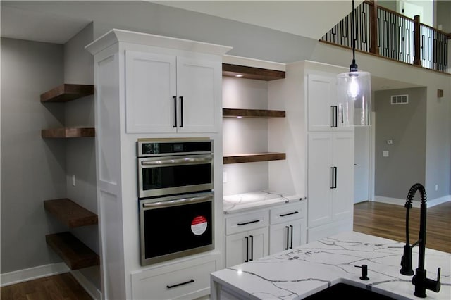 kitchen featuring white cabinetry, stainless steel double oven, open shelves, and visible vents