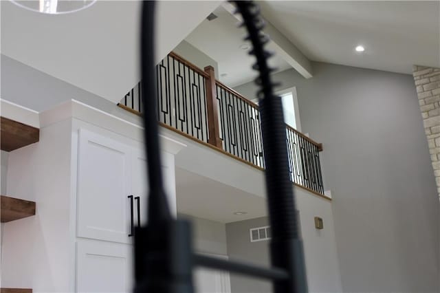 stairway with lofted ceiling with beams and visible vents