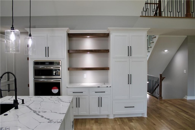 kitchen featuring light wood-style flooring, stainless steel double oven, open shelves, and white cabinets