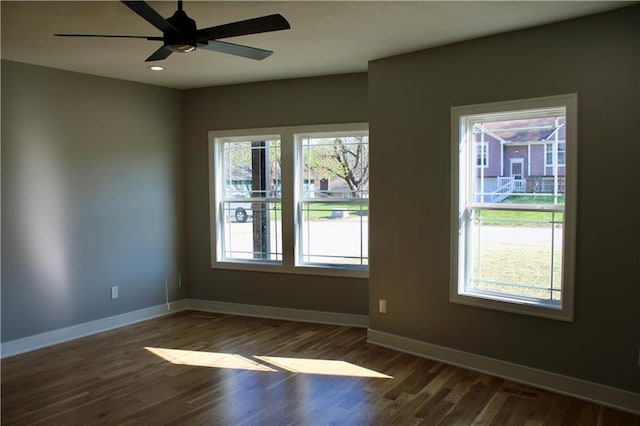 empty room with dark wood-style flooring, baseboards, and a ceiling fan