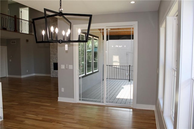 unfurnished dining area with a notable chandelier, baseboards, and wood finished floors