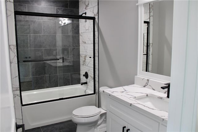 bathroom featuring toilet, vanity, combined bath / shower with glass door, and tile patterned flooring
