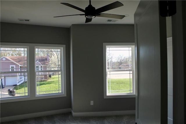 empty room with dark carpet, visible vents, baseboards, and ceiling fan