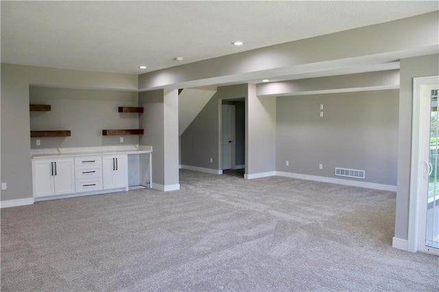 unfurnished living room featuring light colored carpet, baseboards, and visible vents