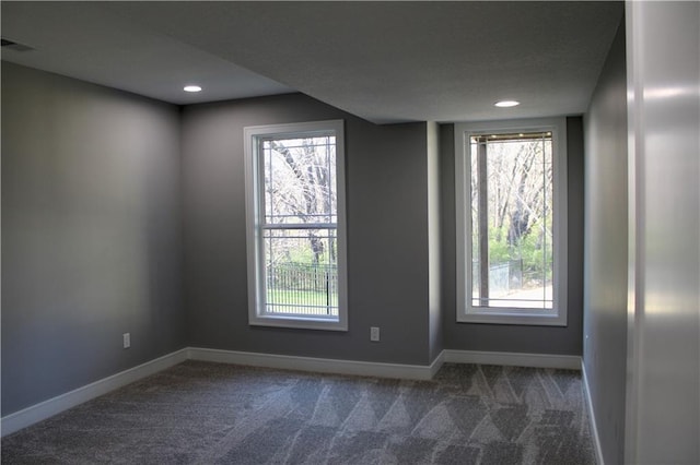 empty room with dark carpet, a healthy amount of sunlight, and baseboards