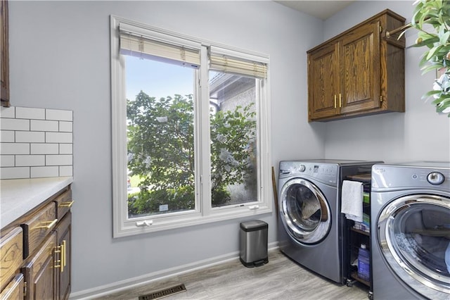 5316 NE Northgate Xing, Lees Summit, MO 64064 - washroom featuring cabinet space, washer and clothes dryer, light wood-style flooring, and baseboards