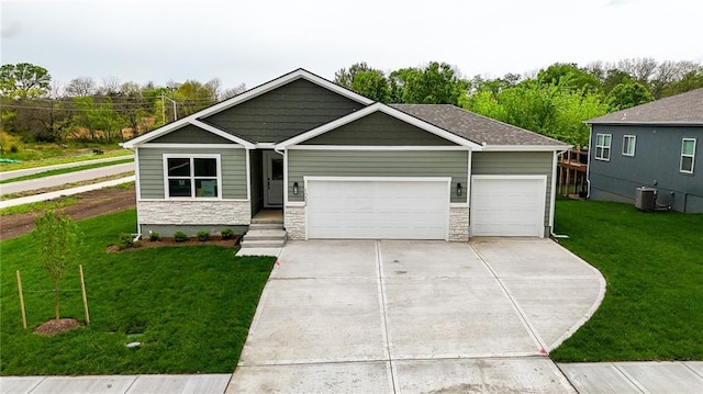 1002 Branchwood Ln, Raymore, MO 64083 - view of front facade featuring stone siding, a garage, a front yard, cooling unit, and driveway