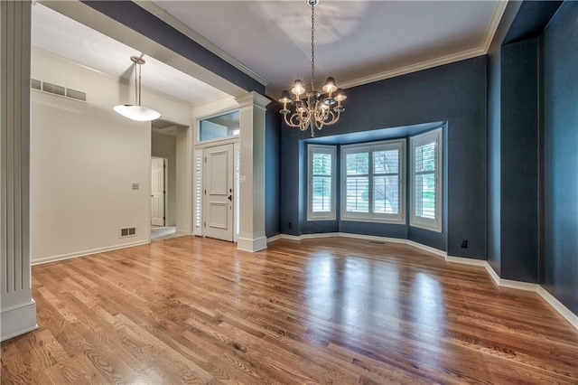 unfurnished dining area featuring ornamental molding, wood finished floors, ornate columns, and baseboards