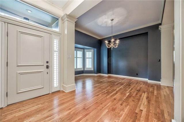 foyer entrance featuring decorative columns, crown molding, a chandelier, light wood-type flooring, and baseboards