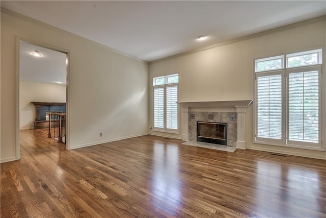 unfurnished living room with a high end fireplace, ornamental molding, wood finished floors, and baseboards