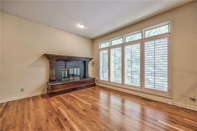 unfurnished living room with a fireplace, wood finished floors, and baseboards