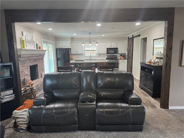 living area with recessed lighting, a barn door, a brick fireplace, baseboards, and ornamental molding