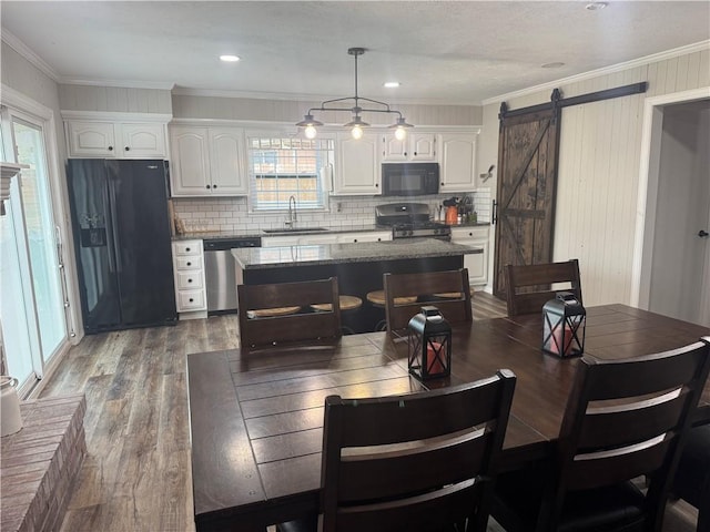 dining room featuring crown molding, a wealth of natural light, wood finished floors, and a barn door