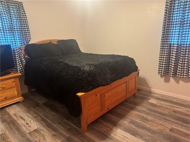 bedroom featuring baseboards and dark wood-type flooring