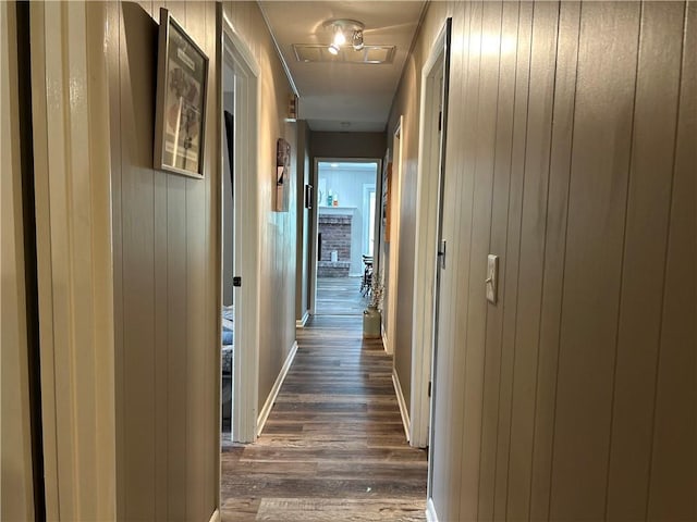 912 Circle Dr, Independence, KS 67301 - hall with dark wood-type flooring, wood walls, and baseboards
