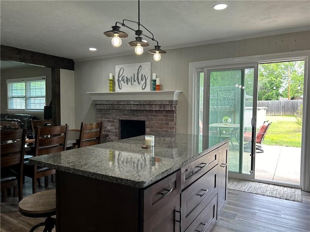 912 Circle Dr, Independence, KS 67301 - kitchen with healthy amount of natural light, wood finished floors, dark stone counters, crown molding, and hanging light fixtures